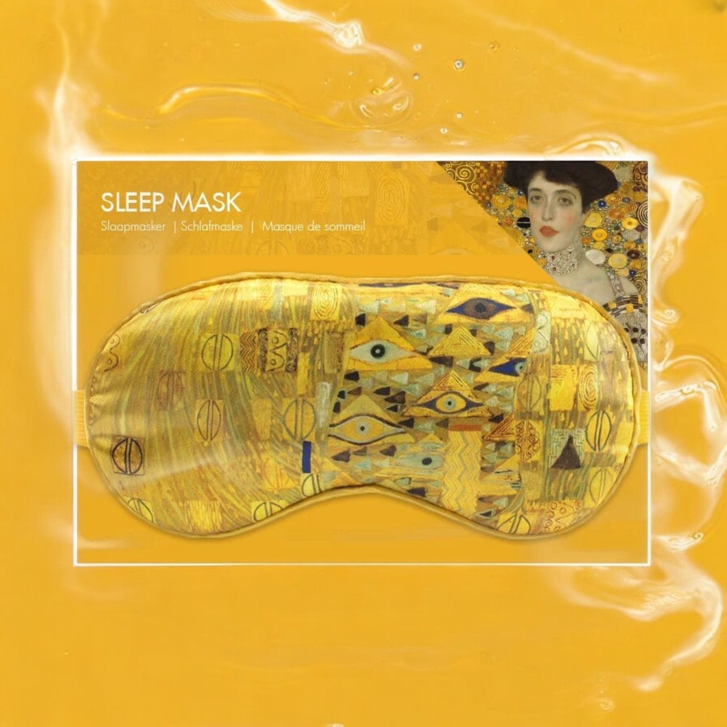 Den gule sovemasken med Gustav Klimt-inspirert design vises i sin emballasje, som har en bakgrunn i matchende gult med teksten "SLEEP MASK" og en del av Klimts verk "Adele Bloch-Bauer I" synlig i hjørnet.